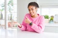 Beautiful african american woman with afro hair wearing casual pink sweater Showing palm hand and doing ok gesture with thumbs up, Royalty Free Stock Photo