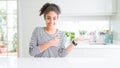 Beautiful african american woman with afro hair wearing casual striped sweater Showing palm hand and doing ok gesture with thumbs Royalty Free Stock Photo