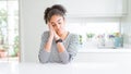 Beautiful african american woman with afro hair wearing casual striped sweater sleeping tired dreaming and posing with hands Royalty Free Stock Photo