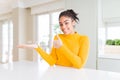Beautiful african american woman with afro hair wearing a casual yellow sweater Showing palm hand and doing ok gesture with thumbs Royalty Free Stock Photo