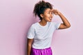 Beautiful african american woman with afro hair wearing sportswear very happy and smiling looking far away with hand over head Royalty Free Stock Photo