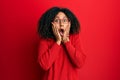 Beautiful african american woman with afro hair wearing sweater and glasses afraid and shocked, surprise and amazed expression Royalty Free Stock Photo