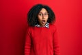 Beautiful african american woman with afro hair wearing sweater and glasses afraid and shocked with surprise and amazed Royalty Free Stock Photo