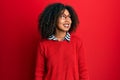 Beautiful african american woman with afro hair wearing sweater and glasses looking away to side with smile on face, natural Royalty Free Stock Photo