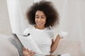 Beautiful African-American woman drinking tea while reading magazine at home Royalty Free Stock Photo