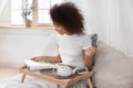 Beautiful African-American woman drinking tea while reading magazine at home Royalty Free Stock Photo