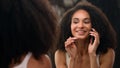 Beautiful African American woman happy smiling girl looking at mirror reflection touch face make up preparing skin care Royalty Free Stock Photo