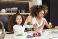 Beautiful African American woman and her daughter coloring Easter eggs in the kitchen