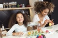 Beautiful African American woman and her daughter coloring Easter eggs in the kitchen Royalty Free Stock Photo