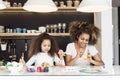 Beautiful African American woman and her daughter coloring Easter eggs in the kitchen Royalty Free Stock Photo