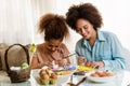 Beautiful African American woman and her daughter coloring Easter eggs Royalty Free Stock Photo