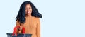 Beautiful african american woman holding supermarket shopping basket looking positive and happy standing and smiling with a Royalty Free Stock Photo