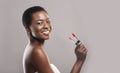 Beautiful african american woman holding two lipsticks in hand Royalty Free Stock Photo