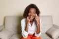 Beautiful african american woman laughing at phone on couch Royalty Free Stock Photo