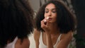 Beautiful African American woman looking in mirror reflection morning beauty routine preparation ethnic girl in bathroom Royalty Free Stock Photo
