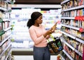 Beautiful African American woman making choice of products at supermarket