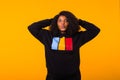 Beautiful African American woman having fun in black sweatshirt on a yellow background. Street fashion photo with afro