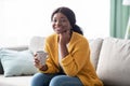 Beautiful african american woman sitting on sofa, drinking tea Royalty Free Stock Photo