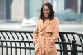 Beautiful african american woman smiling and looking in camera wearing cashmere jacket in the cold winter city. Royalty Free Stock Photo