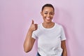 Beautiful african american woman standing over pink background doing happy thumbs up gesture with hand Royalty Free Stock Photo