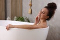 Beautiful African American woman taking bath indoors Royalty Free Stock Photo