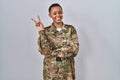 Beautiful african american woman wearing camouflage army uniform smiling with happy face winking at the camera doing victory sign Royalty Free Stock Photo