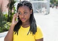 Beautiful african american woman in a yellow shirt listening at mobile phone Royalty Free Stock Photo