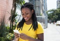 Beautiful african american woman in a yellow shirt texting message with mobile phone Royalty Free Stock Photo