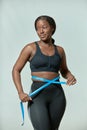 Beautiful african american young plus size body positive woman measure waistline by tape. Weight loss and fitness Royalty Free Stock Photo
