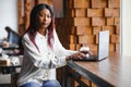 Beautiful african business woman waiting for the meeting in a co-working space and sitting with the portable computer. Hipster Royalty Free Stock Photo