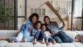 Happy African family with children sitting under symbolic cardboard roof