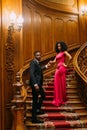 Beautiful african couple posing on the vintage stairs. Luxurious theatre interior background Royalty Free Stock Photo