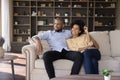 Beautiful African couple relax on couch smile looking into distance Royalty Free Stock Photo