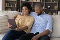 Beautiful African couple relaxing on sofa using digital tablet Royalty Free Stock Photo