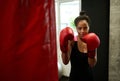 Beautiful African fit woman with perfect physique posing at camera wearing red boxing gloves, hitting punching bag in gym. Female Royalty Free Stock Photo