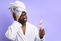 Beautiful african man in bathrobe and towel looking at pink small mirror Royalty Free Stock Photo