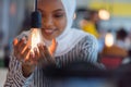 Beautiful african muslim woman holds modern lamp bulb with smiling happy expression, idea concept with selective focus
