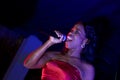 Beautiful African singer woman singing with colorful lights background with her microphone near her mouth Royalty Free Stock Photo