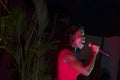 Beautiful African singer woman singing with colorful lights background with her microphone near her mouth Royalty Free Stock Photo