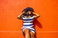 A beautiful African woman in a blue and white striped dress modelling in front of a traditional Bo-Kaap house with orange walls -