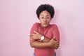 Beautiful african woman with curly hair standing over pink background shaking and freezing for winter cold with sad and shock Royalty Free Stock Photo