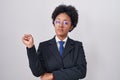 Beautiful african woman with curly hair wearing business jacket and glasses pointing with hand finger to the side showing Royalty Free Stock Photo