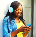Beautiful african woman with headphones listens to music using smartphone Royalty Free Stock Photo