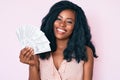 Beautiful african woman holding dollars looking positive and happy standing and smiling with a confident smile showing teeth Royalty Free Stock Photo