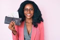 Beautiful african woman holding wallet with dollars looking positive and happy standing and smiling with a confident smile showing Royalty Free Stock Photo