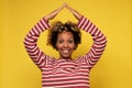 Beautiful african woman with house made of hands on yellow background. Royalty Free Stock Photo