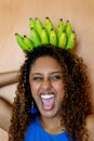 Beautiful african woman with long curly hair smiling holding bunch of bananas as a crown Royalty Free Stock Photo