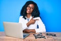 Beautiful african woman at the oculist clinic smiling cheerful pointing with hand and finger up to the side