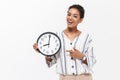 Beautiful african woman posing isolated over white wall background holding time clock