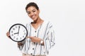 Beautiful african woman posing isolated over white wall background holding time clock